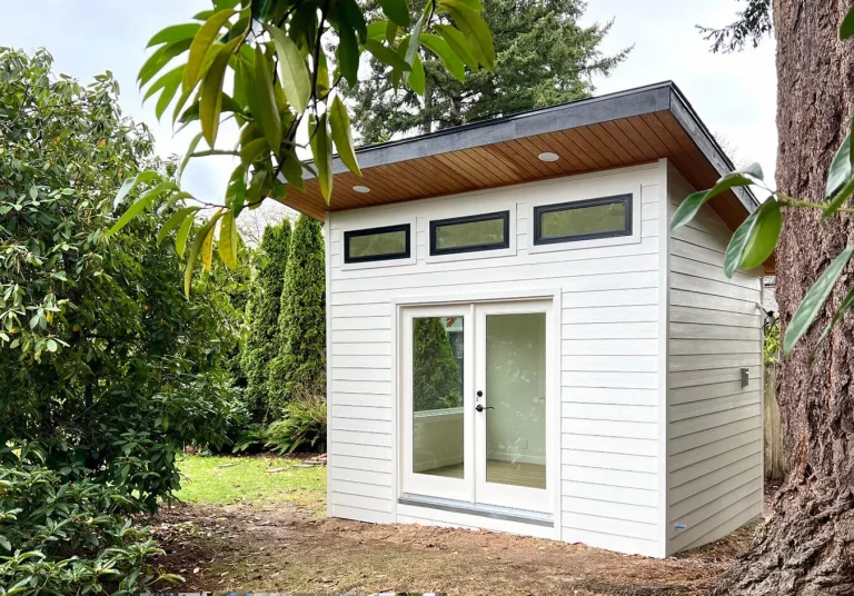 White backyard studio shed with clerestory windows and cedar soffit