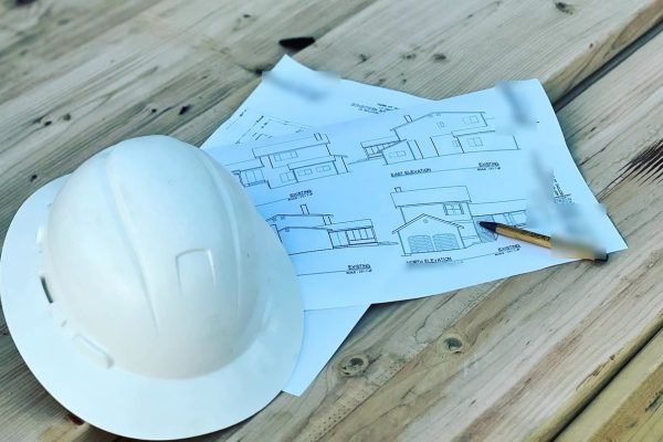 White hard hat and building plans on a wood deck